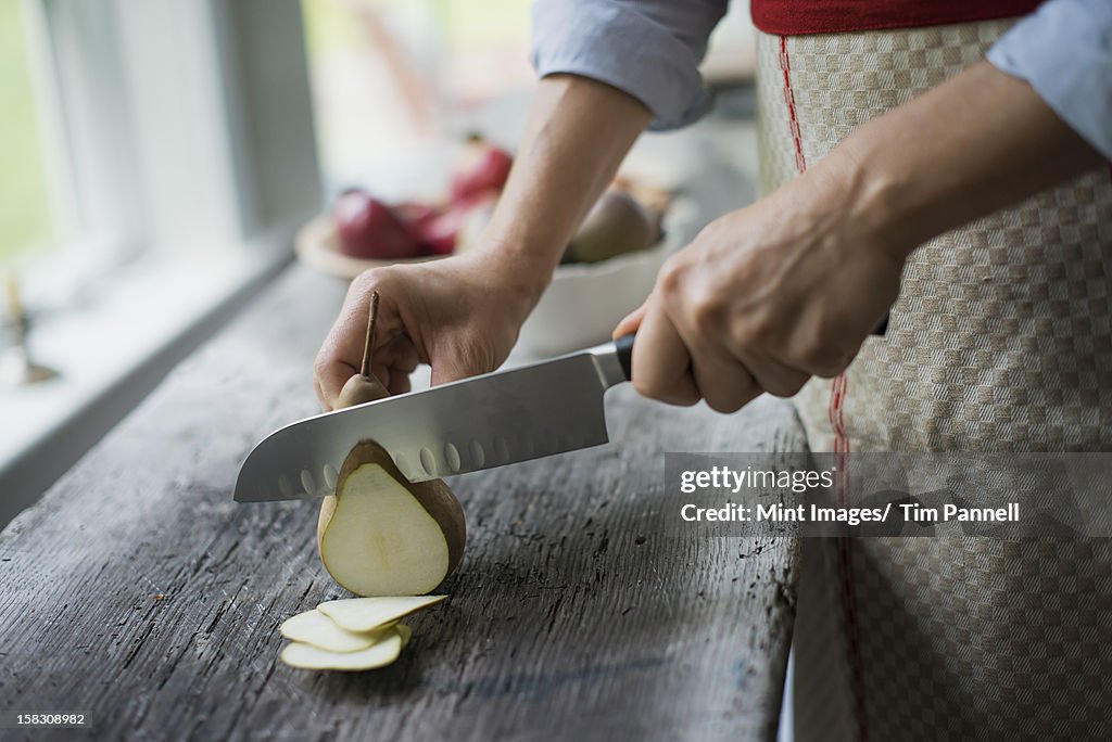 A woman slicing a fresh picked fruit, organic pear. 