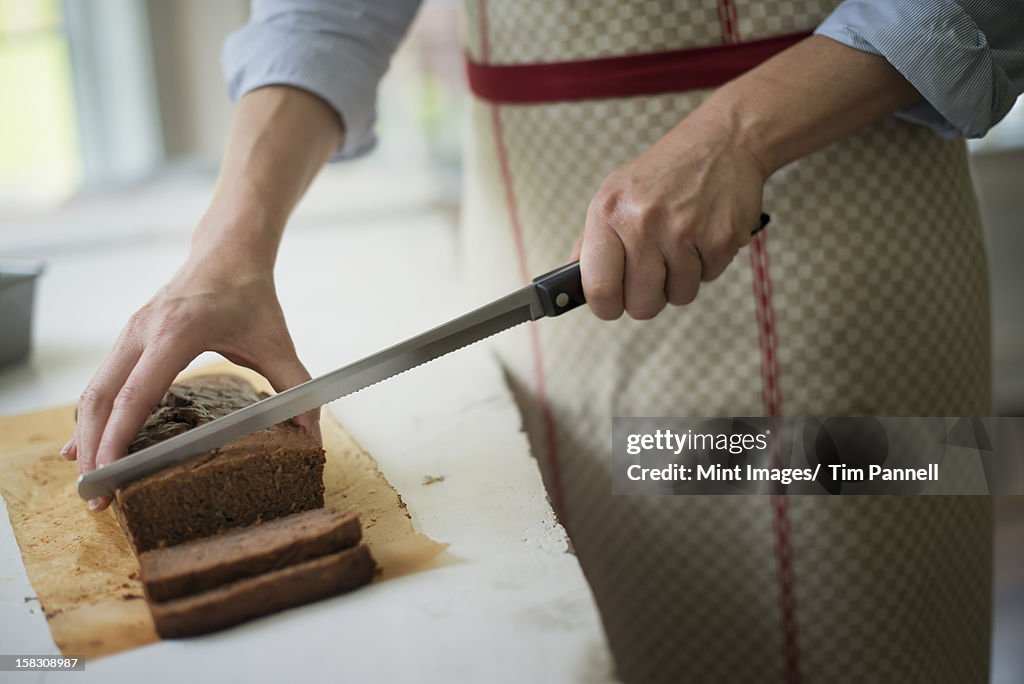 Une femme couper un gâteau de chocolat tout juste sortis du four.