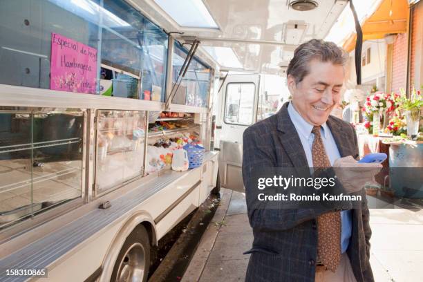 hispanic man text messaging on cell phone on city street - receiving text stock pictures, royalty-free photos & images