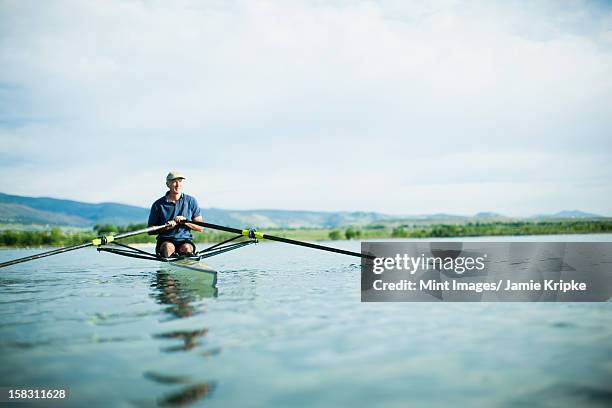 a man in a rowing boat using the oars. - single scull stockfoto's en -beelden