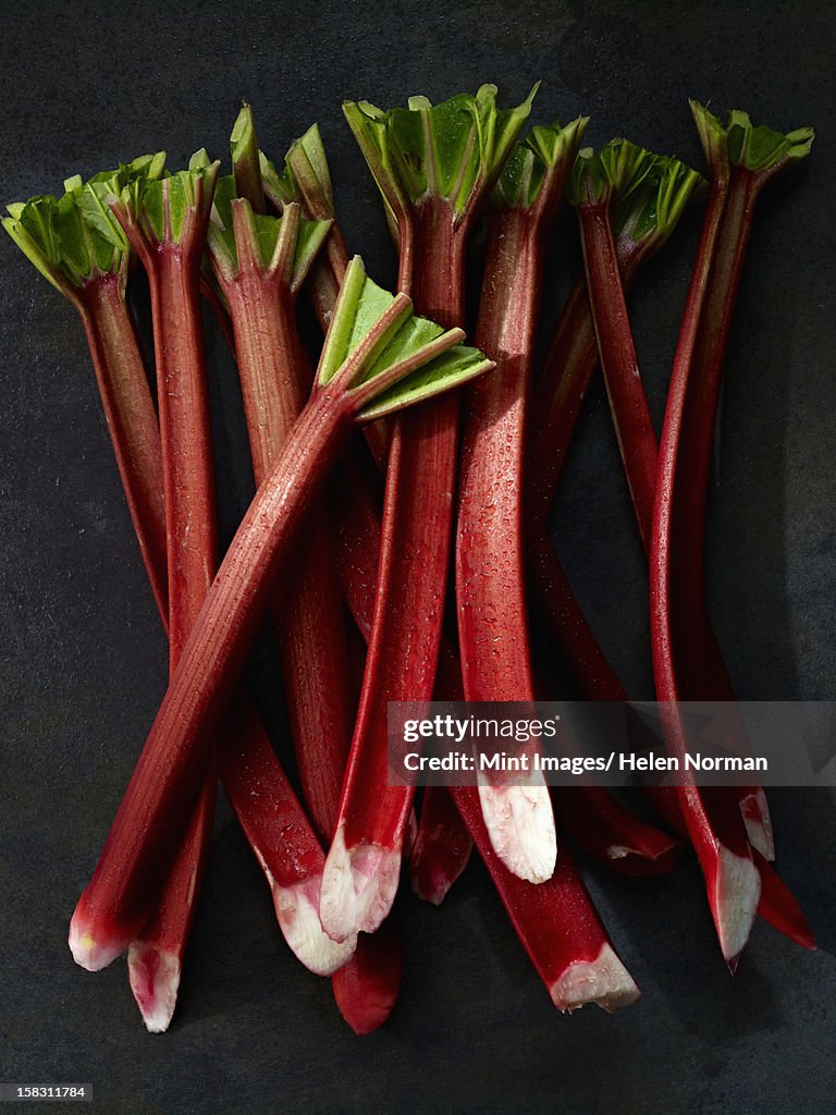 Sticks of fresh rhubarb with long pink stems, and cut leaves.