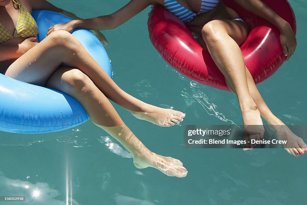 Girls sitting in inflatable rings in swimming pool