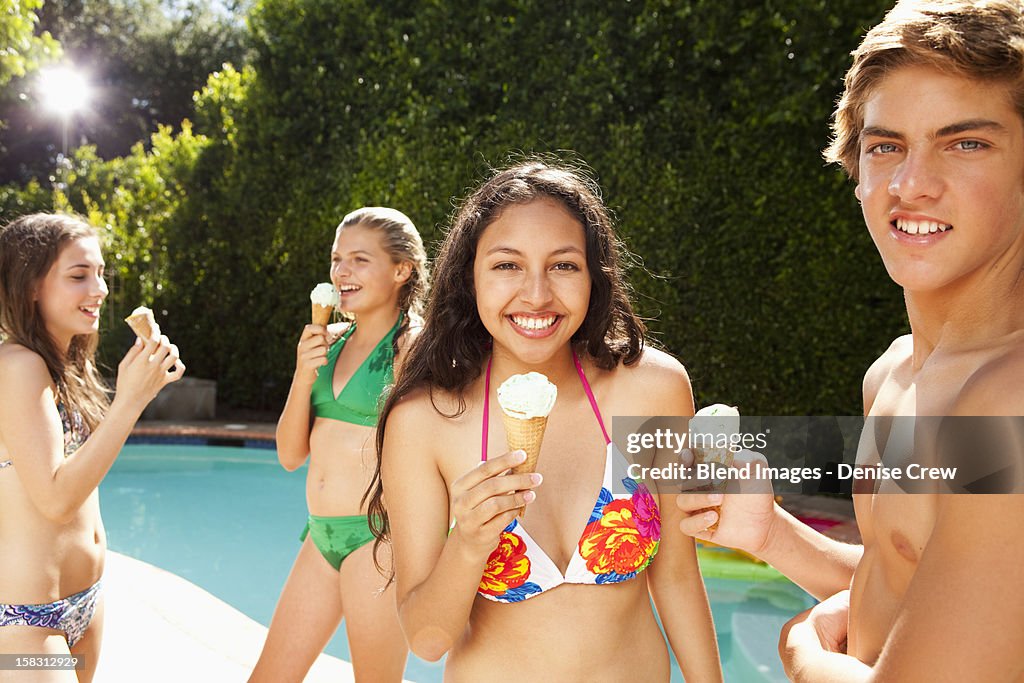 Girls eating ice cream cones near swimming pool