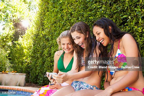 friends sitting by pool looking at cell phone - hot latino girl stock pictures, royalty-free photos & images