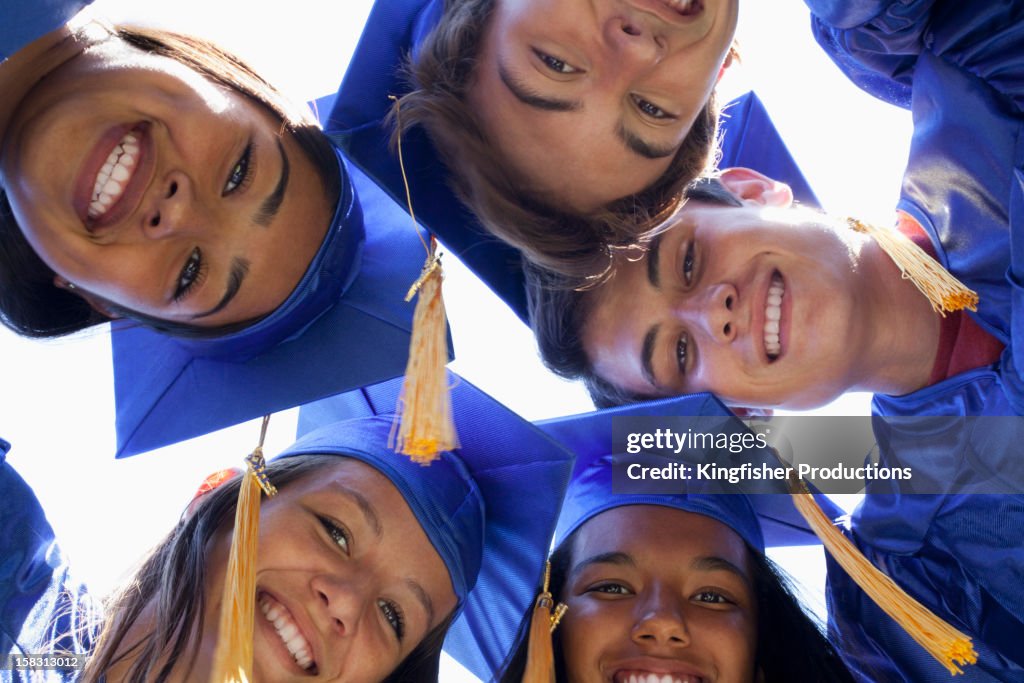 Graduates bending and looking at camera