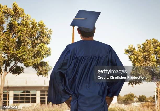 rear view of graduate in cap and gown - togas fotografías e imágenes de stock