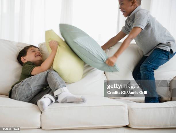 boys rough housing on sofa - pillow fight stock pictures, royalty-free photos & images