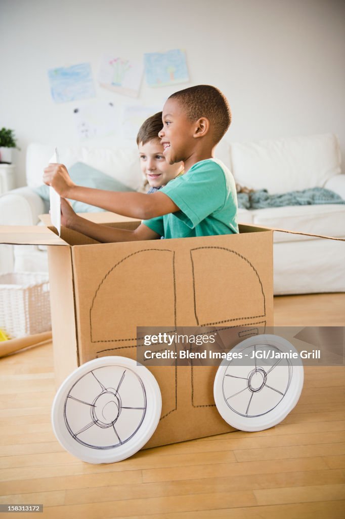 Boys playing in a cardboard car together