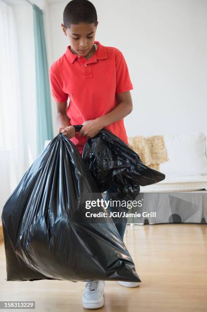 hispanic boy carrying garbage bag - sac poubelle photos et images de collection