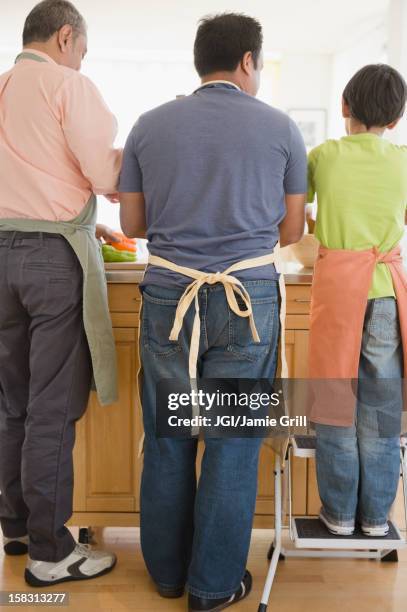 hispanic grandfather, father and son washing dishes - schürze mann rückansicht stock-fotos und bilder