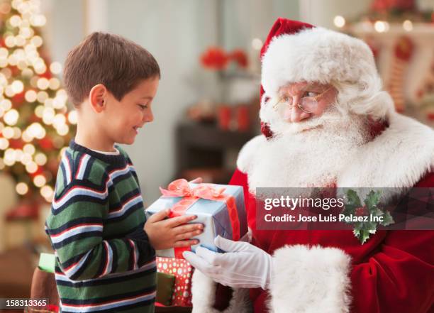 santa giving caucasian boy christmas gift - santa claus stock pictures, royalty-free photos & images