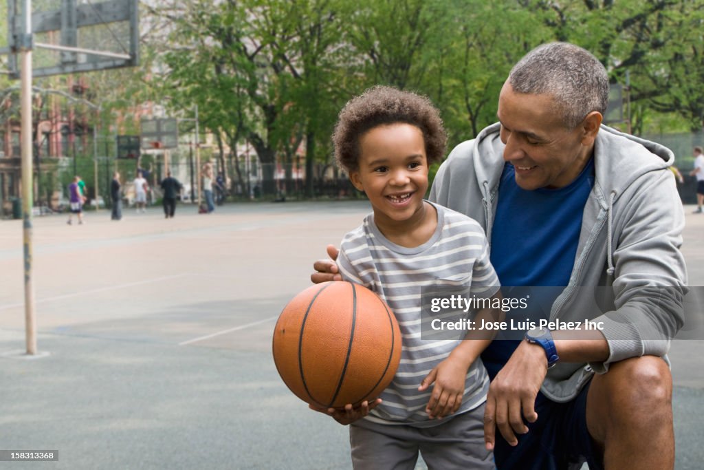 Black father and son playing basketball