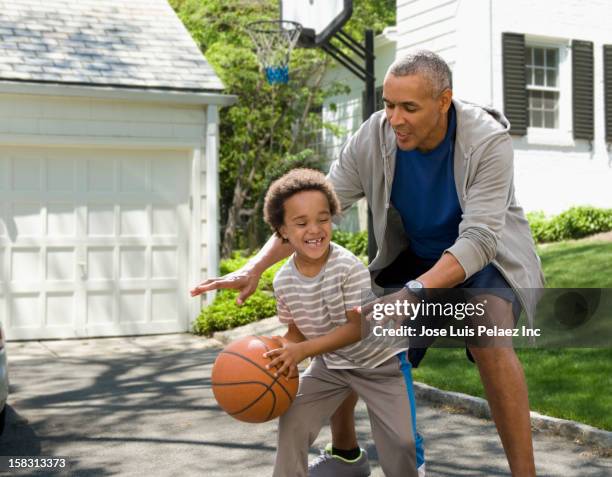 black father and son playing basketball in driveway - drive sportbegriff stock-fotos und bilder