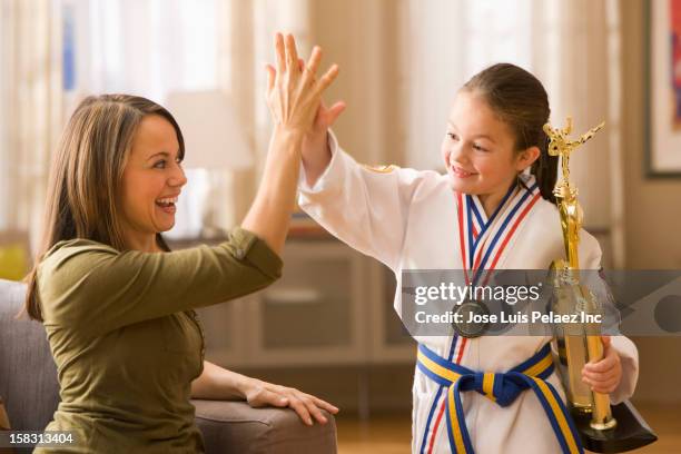 caucasian mother high-fiving daughter for karate win - pride of sport awards stock pictures, royalty-free photos & images