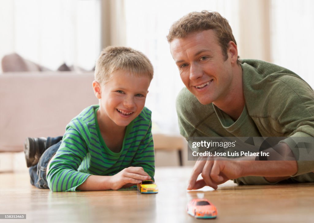 Caucasian father and son playing with toy car on floor