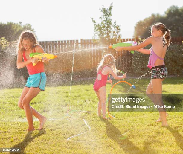 caucasian girls shooting water guns - pistola de agua fotografías e imágenes de stock