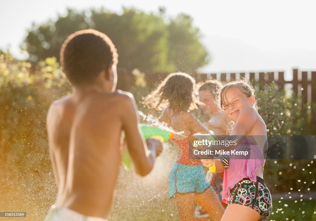 Children squirting each other with water guns