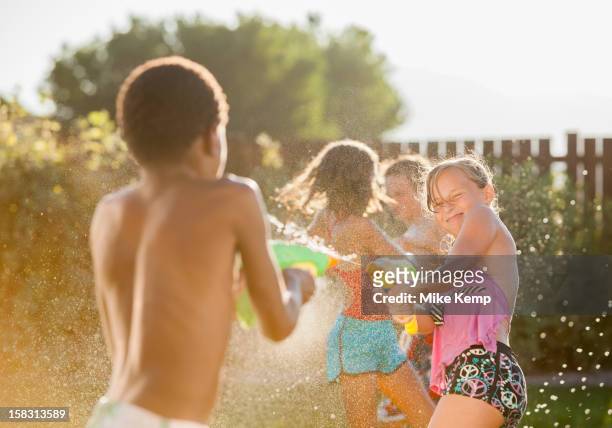children squirting each other with water guns - tween girls hot imagens e fotografias de stock