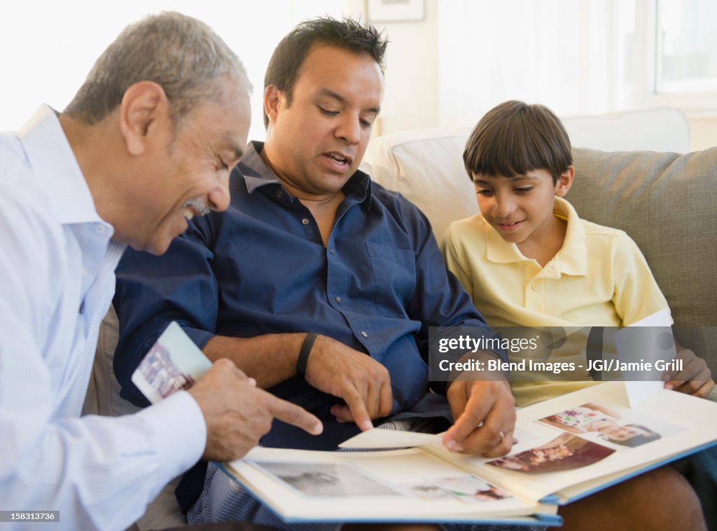 Hispanic grandfather, father and son looking at photo album