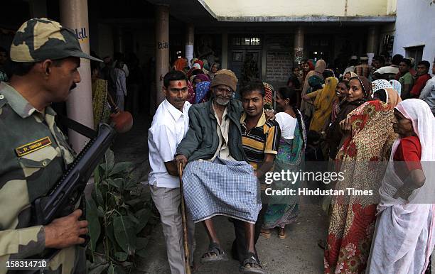 Meru bhai coming out of a polling booth with the help of fellow voters after casting his vote during the first phase polling of Gujarat assembly...