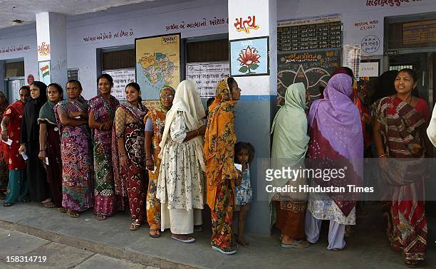 Voters standing in queue to cast their vote as a Lotus flower seen painted at the background which is also the symbol of BJP during the first phase...