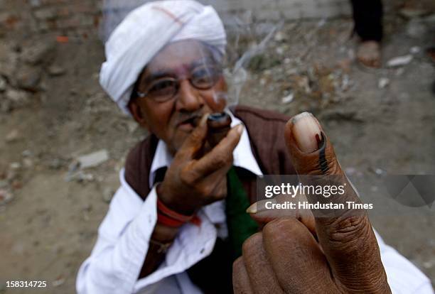 An elderly voter showing the polling mark on his finger after casting vote during the first phase polling of Gujarat assembly election at Sanand on...