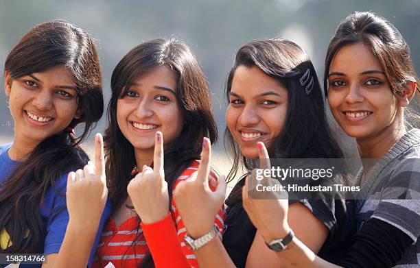 Young voters show off their marked fingers after casting their votes in the first phase polling of Gujarat assembly election on December 13, 2012 in...