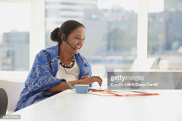 indian businesswoman using headset at desk - laptop headset stock pictures, royalty-free photos & images