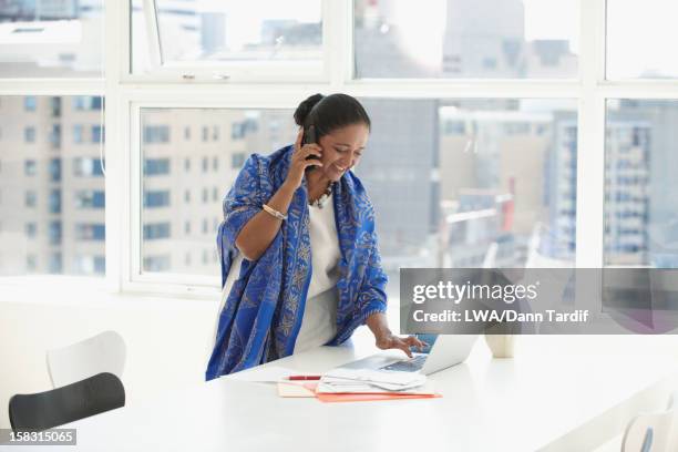 indian businesswoman using cell phone at desk - hair bun scarf woman stock pictures, royalty-free photos & images