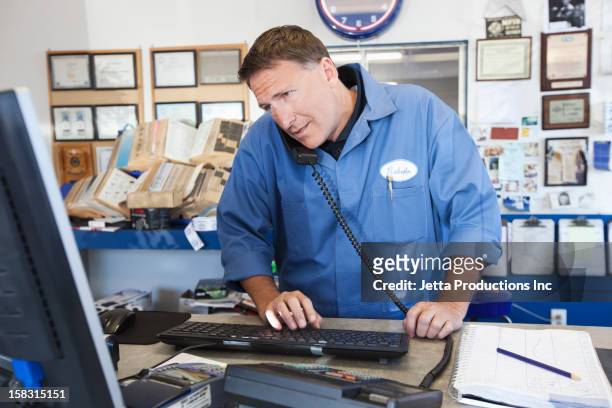 caucasian worker using computer and talking on telephone - repairman phone stock pictures, royalty-free photos & images