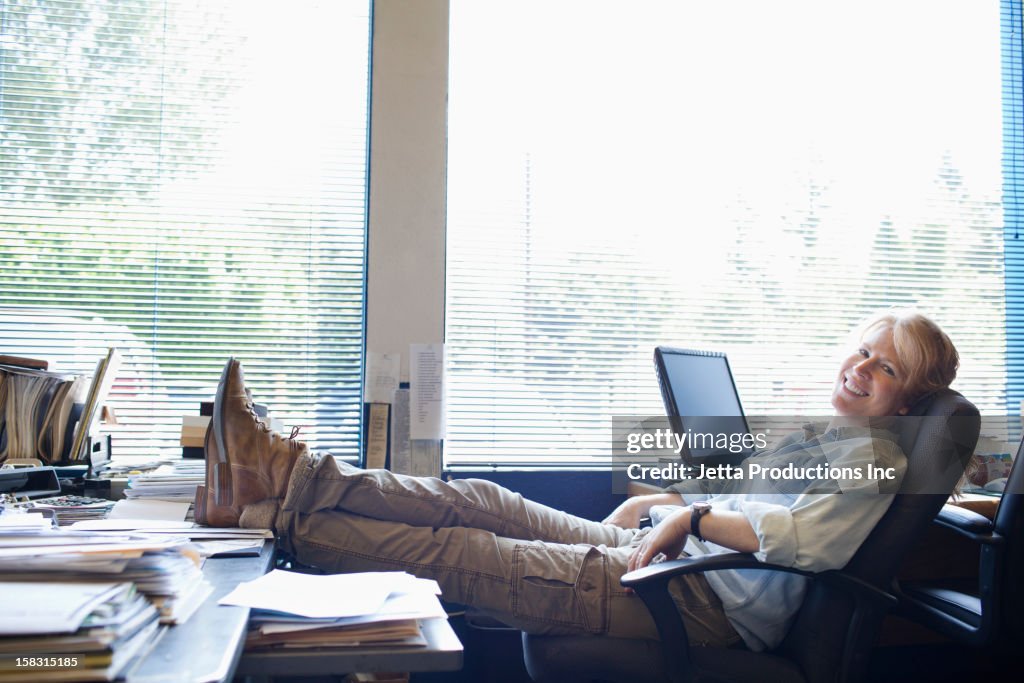 Caucasian woman with feet on desk