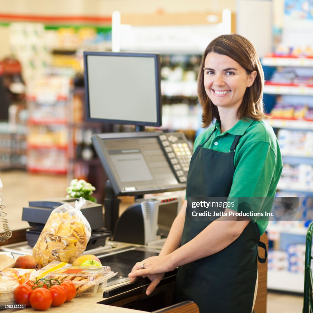 Caucasian worker at register in grocery store