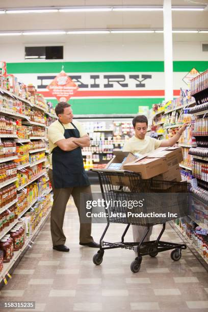 manager watching worker in grocery store - grocery store worker restocking shelves stock pictures, royalty-free photos & images