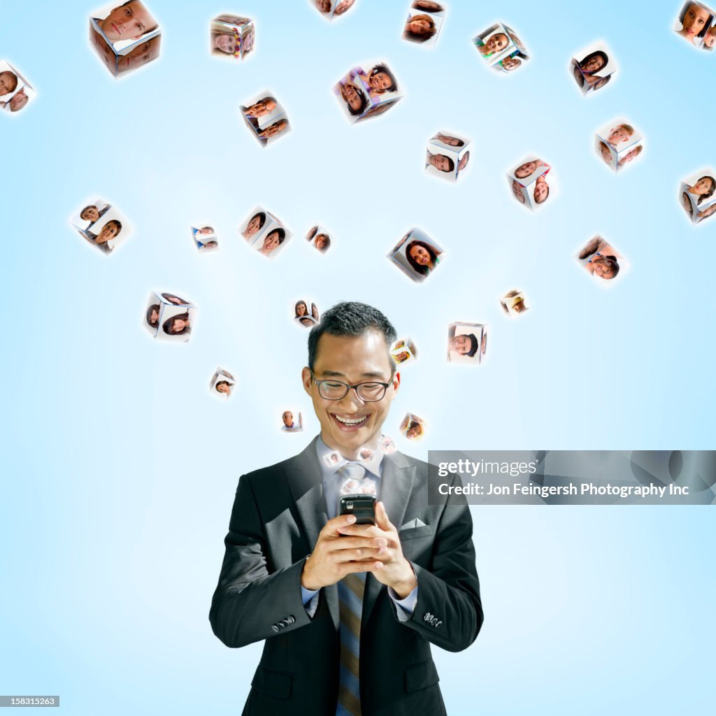 Asian businessman using cell phone with images floating above