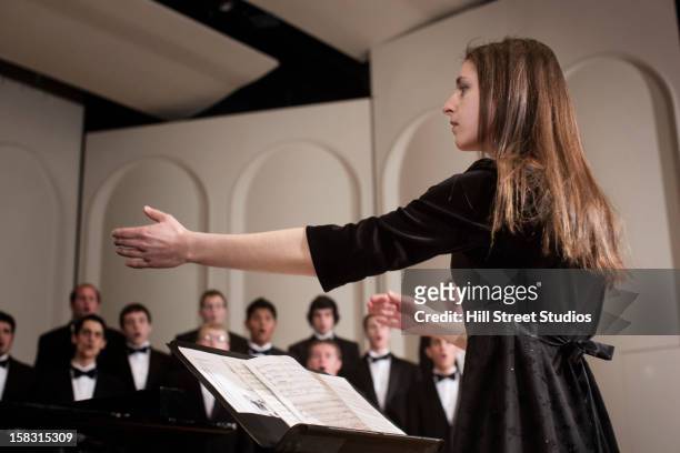 conductor leading choir on stage - coro foto e immagini stock