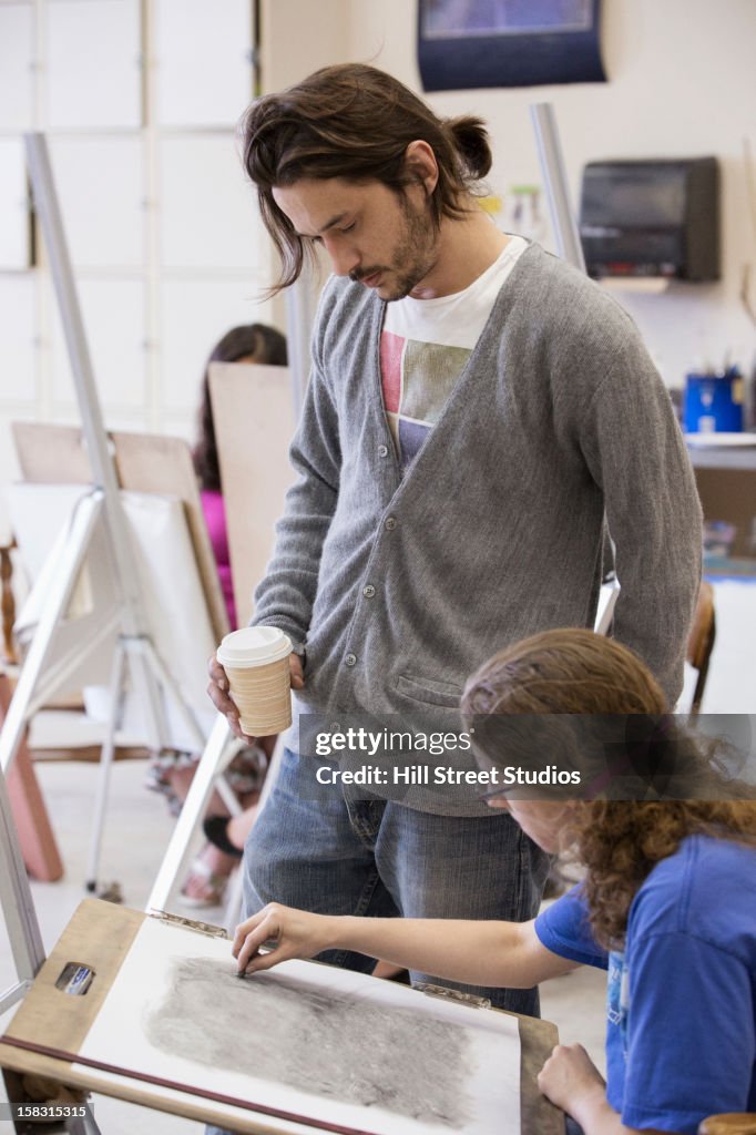 Teacher helping student in art class