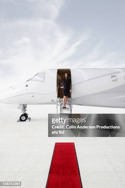 pacific islander stewardess standing in doorway of private jet - rico e anderson fotografías e imágenes de stock