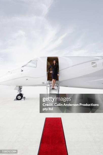 pacific islander stewardess standing in doorway of private jet - airport crew stock pictures, royalty-free photos & images