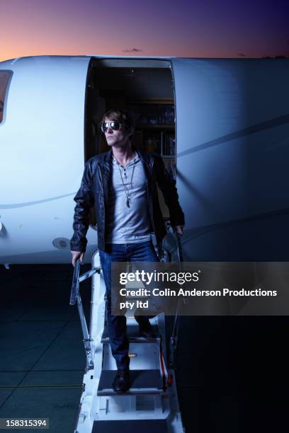 caucasian man walking down steps of private jet - passenger muzikant stockfoto's en -beelden