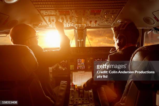 caucasian pilots flying jet at sunset - cabine imagens e fotografias de stock