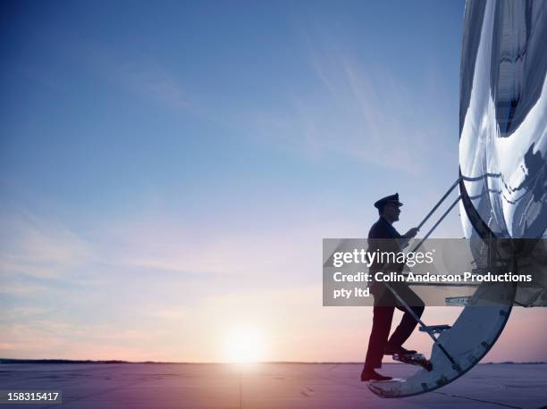 caucasian pilot walking up steps of jet - piloto fotografías e imágenes de stock