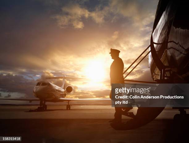caucasian pilot walking down steps of jet - airline pilot imagens e fotografias de stock