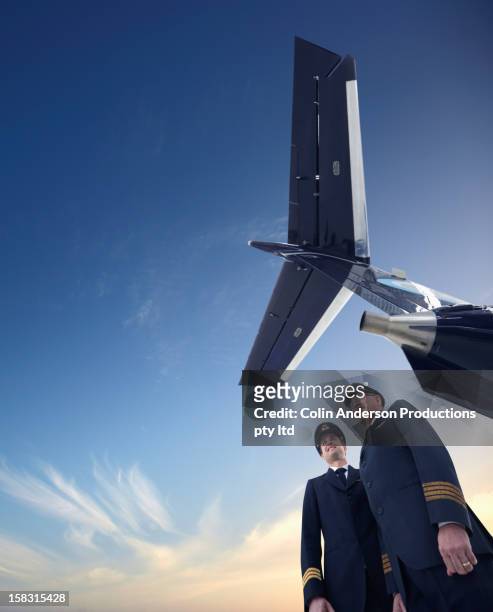 caucasian pilots standing underneath airplane - 機体尾部 ストックフォトと画像