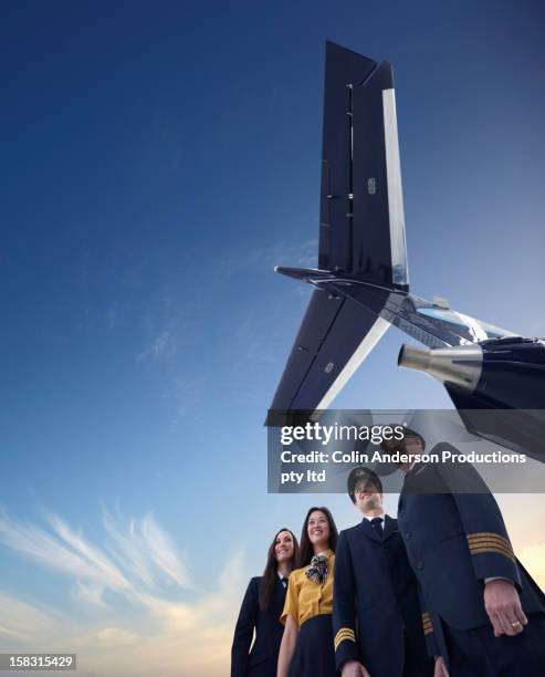 pilots and flight staff standing underneath airplane - civil aviation stock pictures, royalty-free photos & images