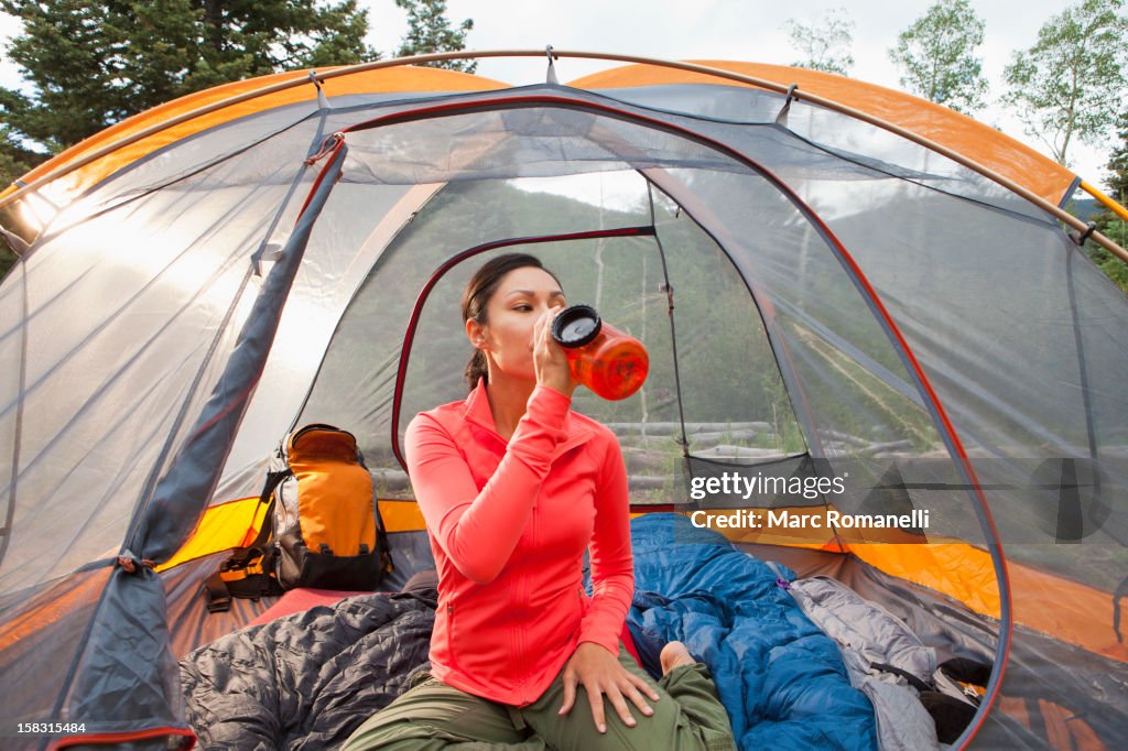 Mixed race woman drinking in tent