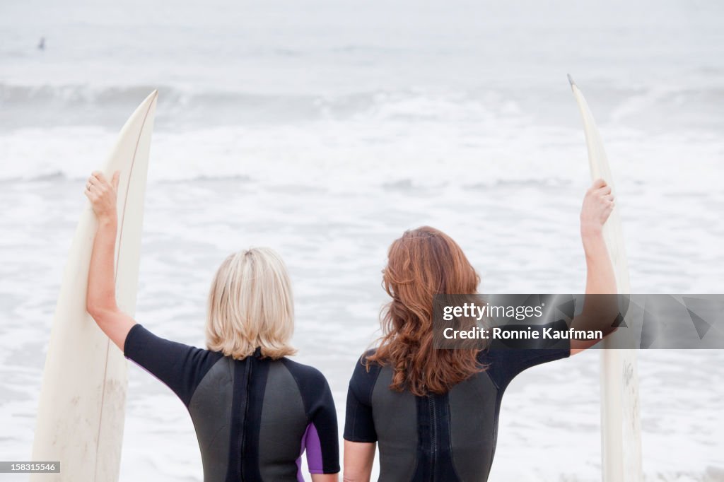 Caucasian women standing with surfboards