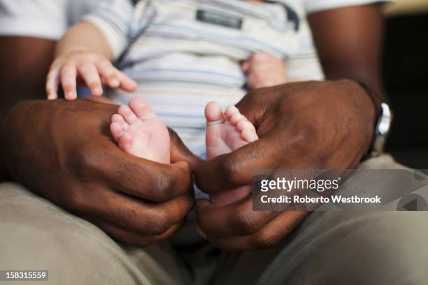 father holding baby's small feet - little feet stock pictures, royalty-free photos & images