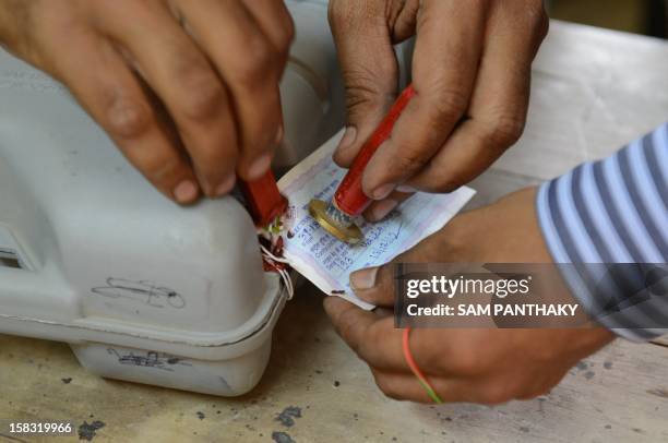 Indian officials seal an Electronic Voting Machine at a voting centre for the state assembly elections at Viramgam, 60 kms from Ahmedabad on December...