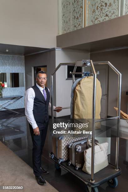 portrait of porter in hotel with luggage trolley - turismo responsable fotografías e imágenes de stock