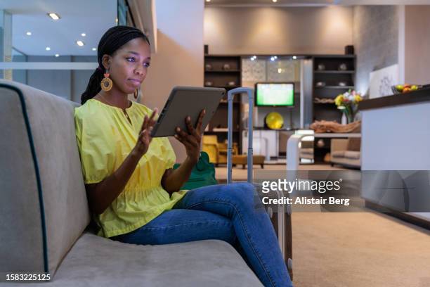 young woman using digital tablet computer in hotel lobby - business journey stock pictures, royalty-free photos & images